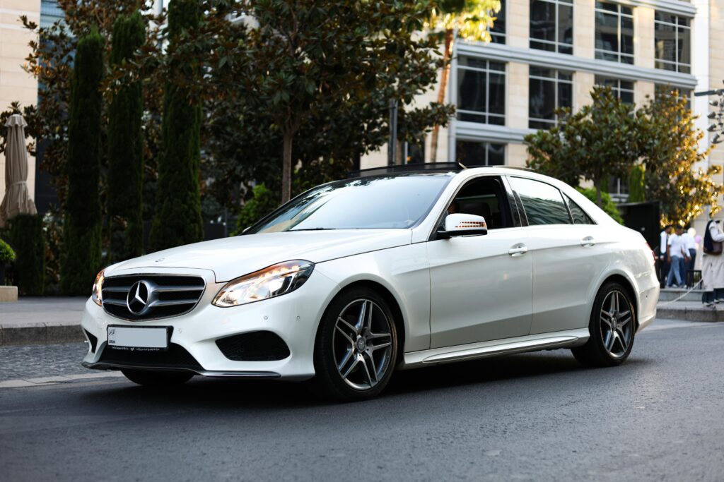 A sleek white Mercedes-Benz sedan elegantly displayed in an urban street of Amman, Jordan. Perfect for automotive enthusiasts.